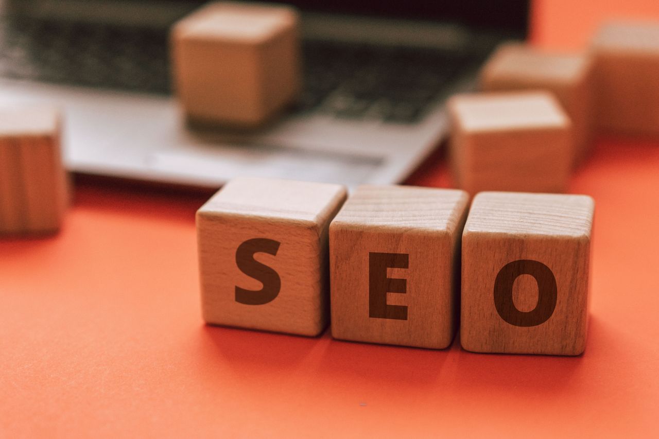 Des blocs de bois formant SEO sur le clavier d’un ordinateur portable illustrent des concepts de marketing digital.
